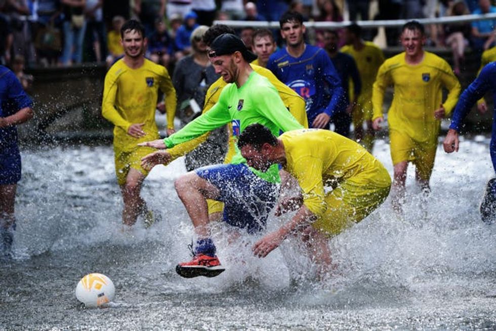 Annual river football clash goes ahead despite waterlogged pitch | indy100