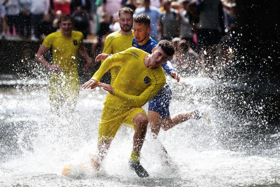 Annual river football clash goes ahead despite waterlogged pitch | indy100